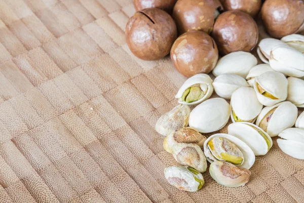 Macadamia och pistage nötter på bord av trä. — Stockfoto