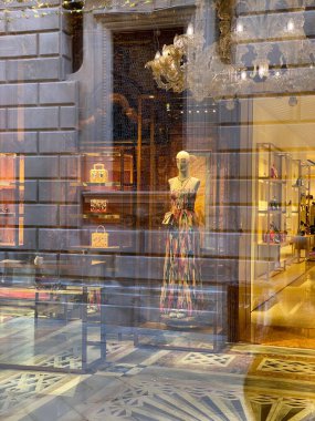 Covid-19 yüzünden kapalı olan bir moda mağazasının penceresinin önünde yürüyen birinin yansıması. Pencereden bir manken görebiliriz..