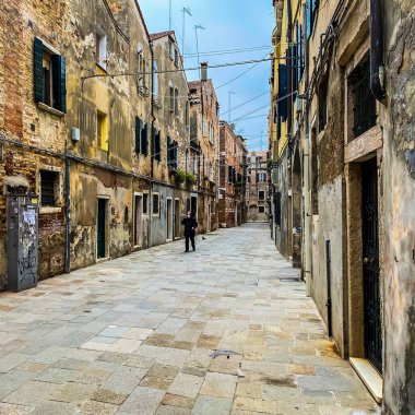 Venedik, İtalya, 19 Şubat 2021 - Korumalı bir maskeyle telefonla konuşan ve kriz sırasında yalnız yürüyen tanınmayan insanlar