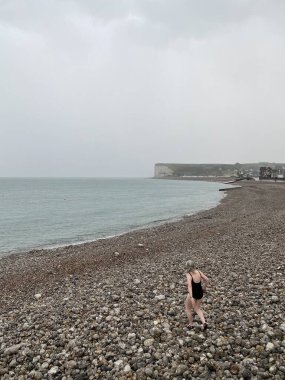 Tanımlanamayan kadın yüzücü yağmurda, Opal Sahili 'nde, Normandiya, Fransa' da yüzmeye gidiyor.