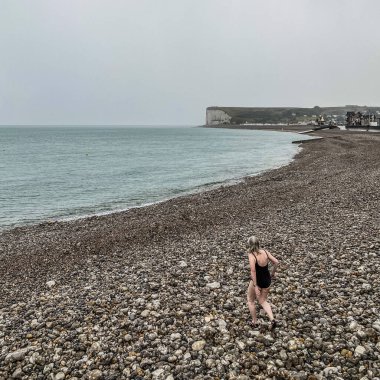 Tanımlanamayan kadın yüzücü yağmurda, Opal Sahili 'nde, Normandiya, Fransa' da yüzmeye gidiyor.