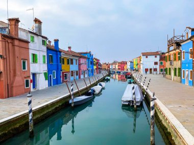 Burano Adası, Venedik 'teki kanal evlerinde tekneler ve renkli evler, arka planda tanınmayan insanlar..