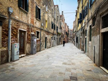 Venedik, İtalya, 19 Şubat 2021 - Korumalı bir maskeyle telefonla konuşan ve kriz sırasında yalnız yürüyen tanınmayan insanlar