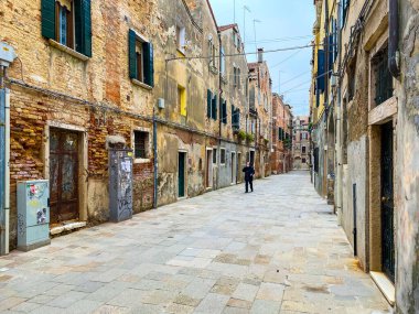 Venedik, İtalya, 19 Şubat 2021 - Korumalı bir maskeyle telefonla konuşan ve kriz sırasında yalnız yürüyen tanınmayan insanlar