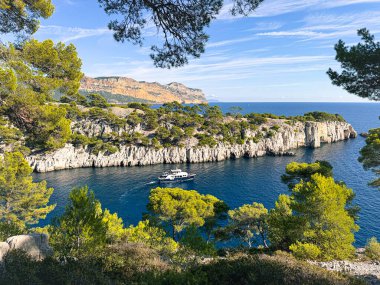 Calanque d 'en vau mavi suyu, beyaz uçurumları ve manzaralı körfezde gezinen bir tekneyi gösteriyor.