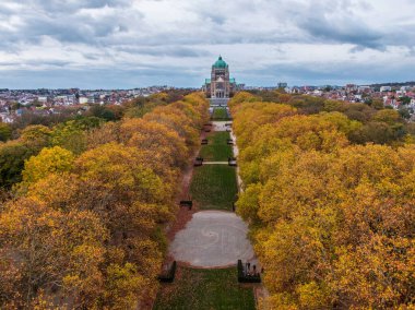 Koekelberg Bazilikası, Brüksel 'deki bir şehir parkındaki sonbahar ağaçlarını değiştirerek çerçevelenmiştir.