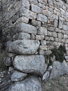 Kaba, yıpranmış granit bloklar ve Cevennes 'deki yeşil bitki örtüsüyle inşa edilmiş taş duvar köşesi.