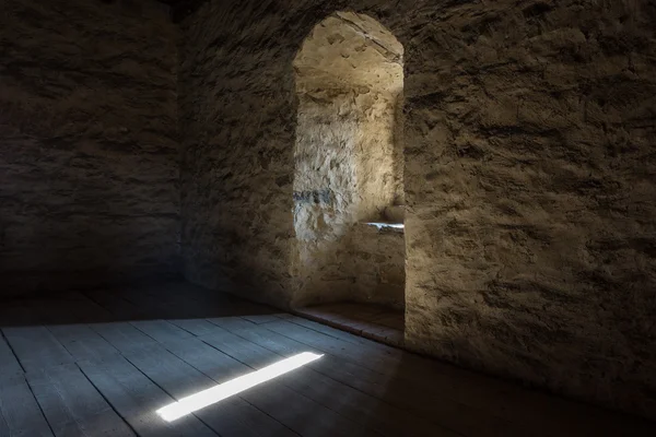 Quarto escuro com paredes de pedra janela e escada de madeira — Fotografia de Stock