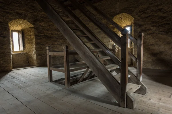 Quarto escuro com paredes de pedra janela e escada de madeira — Fotografia de Stock