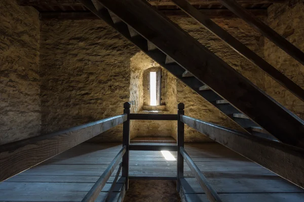 Quarto escuro com paredes de pedra janela e escada de madeira — Fotografia de Stock