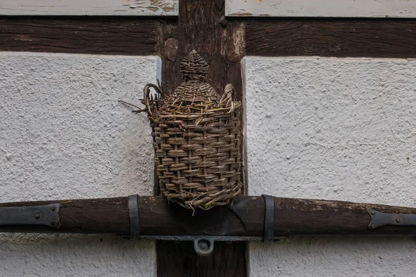 Die alte Wippe und der Korb an der Wand des Bauernhauses — Stockfoto