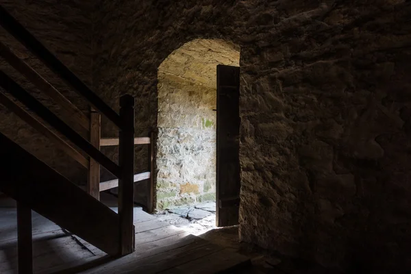 Taş duvarlar pencere ve Ahşap merdiven karanlık oda — Stok fotoğraf