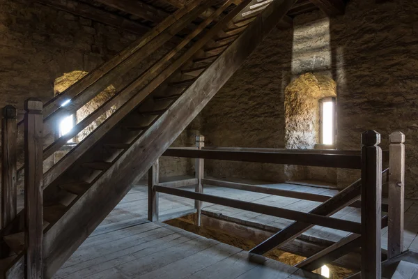 Quarto escuro com paredes de pedra janela e escada de madeira — Fotografia de Stock