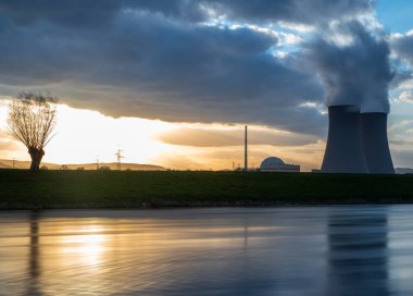 Gün batımında nehir kenarında gökyüzüne karşı nükleer enerji santrali