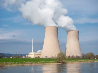 Gün batımında nehir kenarında gökyüzüne karşı nükleer enerji santrali