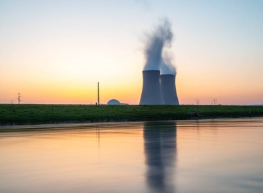 Gün batımında nehir kenarında gökyüzüne karşı nükleer enerji santrali
