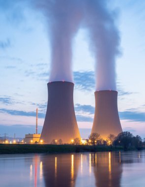 Gün batımında nehir kenarında gökyüzüne karşı nükleer enerji santrali