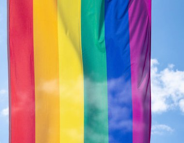 Mavi gökyüzüne karşı gün ışığında gökkuşağı bayrağı