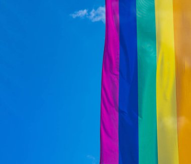 Mavi gökyüzüne karşı gün ışığında gökkuşağı bayrağı