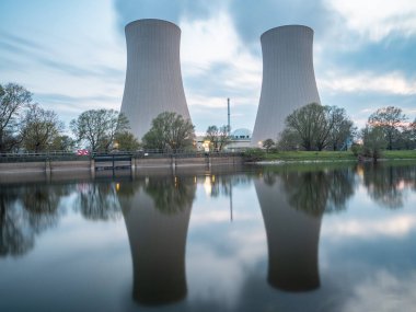 Gün batımında nehir kenarında gökyüzüne karşı nükleer enerji santrali
