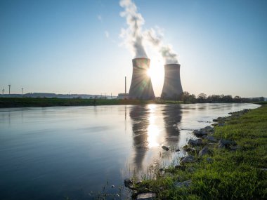 Gün batımında nehir kenarında gökyüzüne karşı nükleer enerji santrali