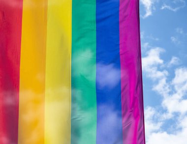 Mavi gökyüzüne karşı gün ışığında gökkuşağı bayrağı