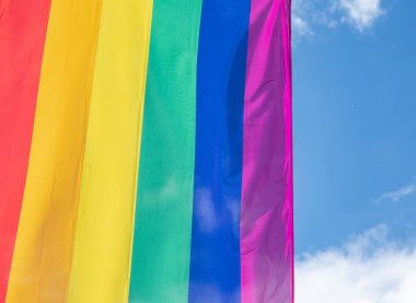 Mavi gökyüzüne karşı gün ışığında gökkuşağı bayrağı