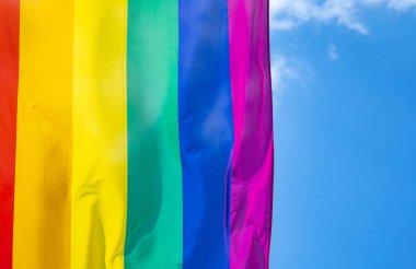 Mavi gökyüzüne karşı gün ışığında gökkuşağı bayrağı