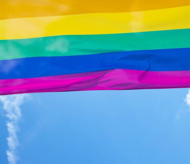 Mavi gökyüzüne karşı gün ışığında gökkuşağı bayrağı