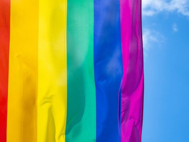 Mavi gökyüzüne karşı gün ışığında gökkuşağı bayrağı