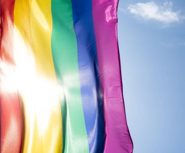 Mavi gökyüzüne karşı gün ışığında gökkuşağı bayrağı