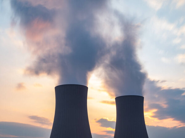 Nuclear power plant against sky at sunset