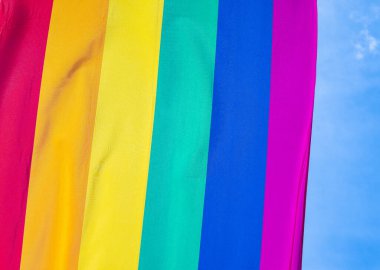 Mavi gökyüzüne karşı gün ışığında gökkuşağı bayrağı