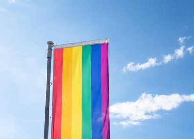 Mavi gökyüzüne karşı gün ışığında gökkuşağı bayrağı