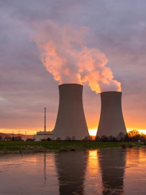 Gün batımında nehir kenarında gökyüzüne karşı nükleer enerji santrali