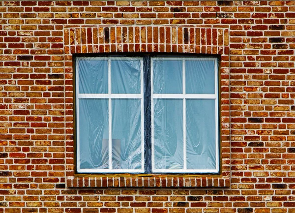 Fenster unter der Plastikfolie in Ziegelwand — Stockfoto
