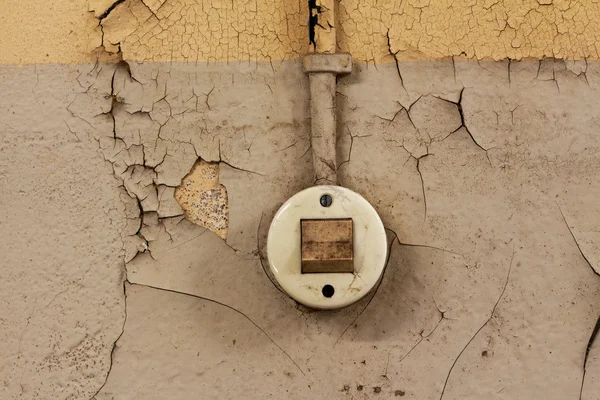 De oude elektrische switch en de kabel op een afgeleefde muur — Stockfoto