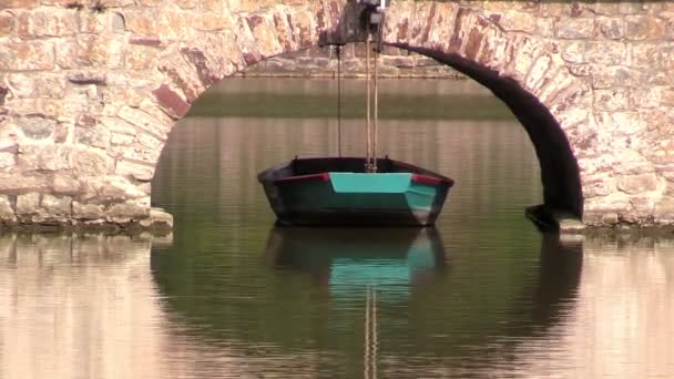 Tied boat near the bridge on pond — Stock Video