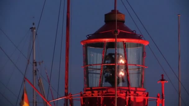 Rotating lighthouse at dusk in harbor — Stock Video