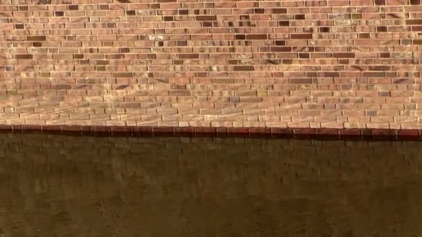 Brick wall and current river water in sunlight — Stock Video