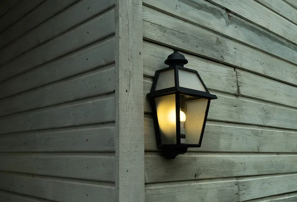 Elektrische lamp op een muur van houten huis — Stockfoto