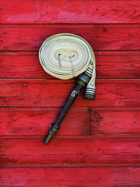 Hank fire hose on a red wooden wall clipart