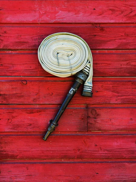 Hank fire hose on a red wooden wall — Stock Photo, Image
