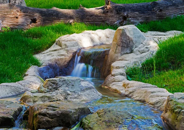 Cascade sur le ruisseau qui coule à travers l'herbe verte — Photo