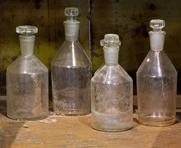 Las viejas botellas de vidrio reactivo en la mesa polvorienta — Foto de Stock