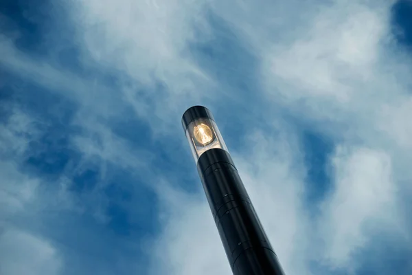 Luz de calle moderna contra el cielo y las nubes en el crepúsculo — Foto de Stock