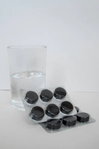 Medicin, tabletter og spray med et glas vand på en lys baggrund - Stock-foto
