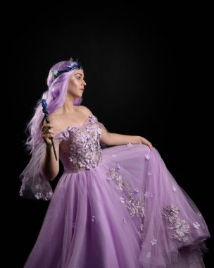 Kelebek kaplamalı ve pembe saçlı uzun mor fantezi balo elbisesi giyen kızın yakın plan portresi..