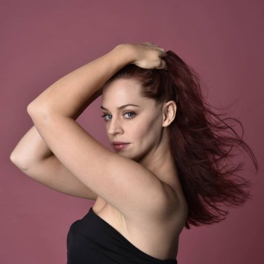 Pembe stüdyo arka planında anlamlı yüz hatları olan kızıl saçlı bir kadının portresi..