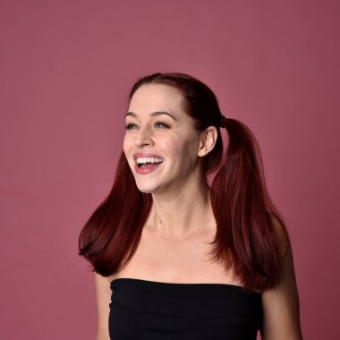 Pembe stüdyo arka planında anlamlı yüz hatları olan kızıl saçlı bir kadının portresi..